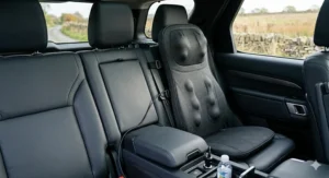 A portable full back massage cushion fitted onto a leather car seat with a 12V cigarette lighter adapter