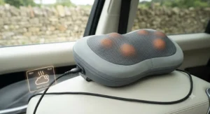 A heated car travel massage pillow glowing softly, illustrating soothing warmth for aching muscles during motorway driving.