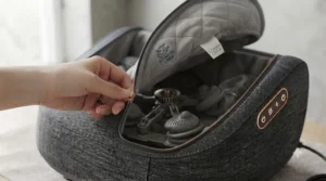 A close-up of a hand fully unzipping the quilted grey washable liner from the dark grey foot massager, exposing the intricate internal roller mechanism.